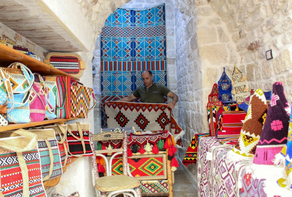 Syrian trader, Mahmoud Khojah, works inside his shop which has reopened after undergoing extensive restoration after enduring significant damage from the Syrian war, at Aleppo's old souks, in Aleppo, Syria August 28, 2024. REUTERS/Firas Makdesi
