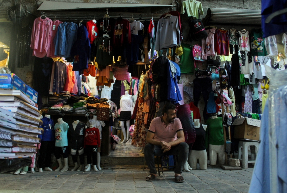 A man sits outside his shop which has reopened after undergoing extensive restoration after enduring significant damage from the Syrian war, at Aleppo's old souks, in Aleppo, Syria August 28, 2024. REUTERS/Firas Makdesi
