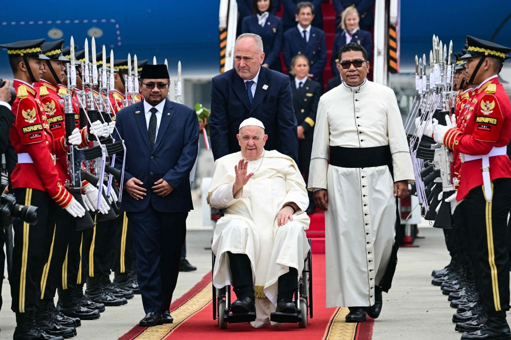 Pope Francis (C, in wheelchair) is welcomed during his arrival at Soekarno Hatta International Airport in Jakarta. — AFP 