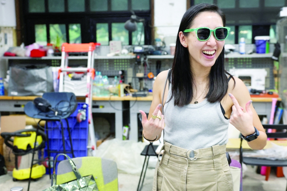 Debbie Wu tests her pair of sunglasses made from plastic waste at Trash Kitchen in Taipei, Taiwan August 19, 2024. 
