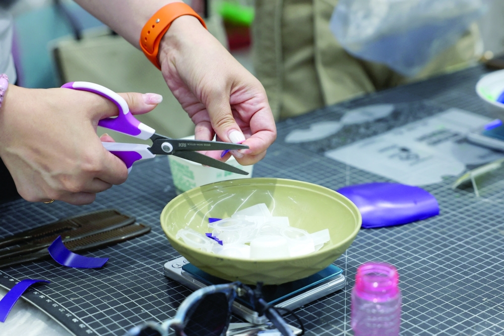 A person cuts up plastic waste to be used as part of her sunglasses at Trash Kitchen in Taipei, Taiwan.