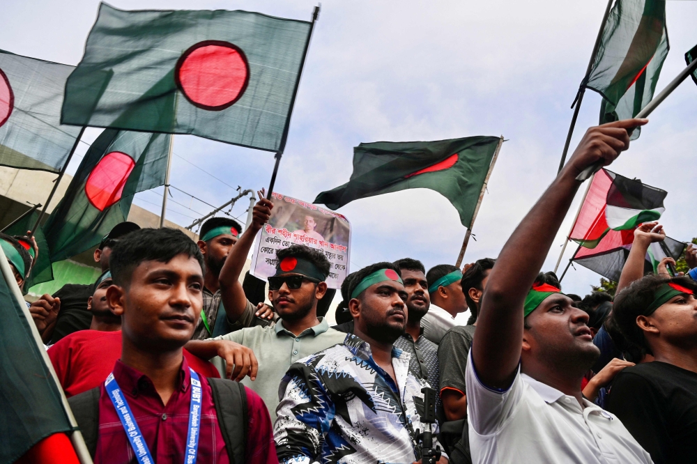 Demonstrators wave Bangladesh's national flag during Martyr March in Dhaka. - AFP