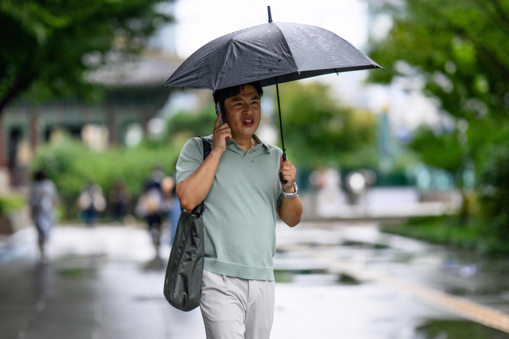 A man uses an umbrella during a light rain shower in Seoul. - AFP
