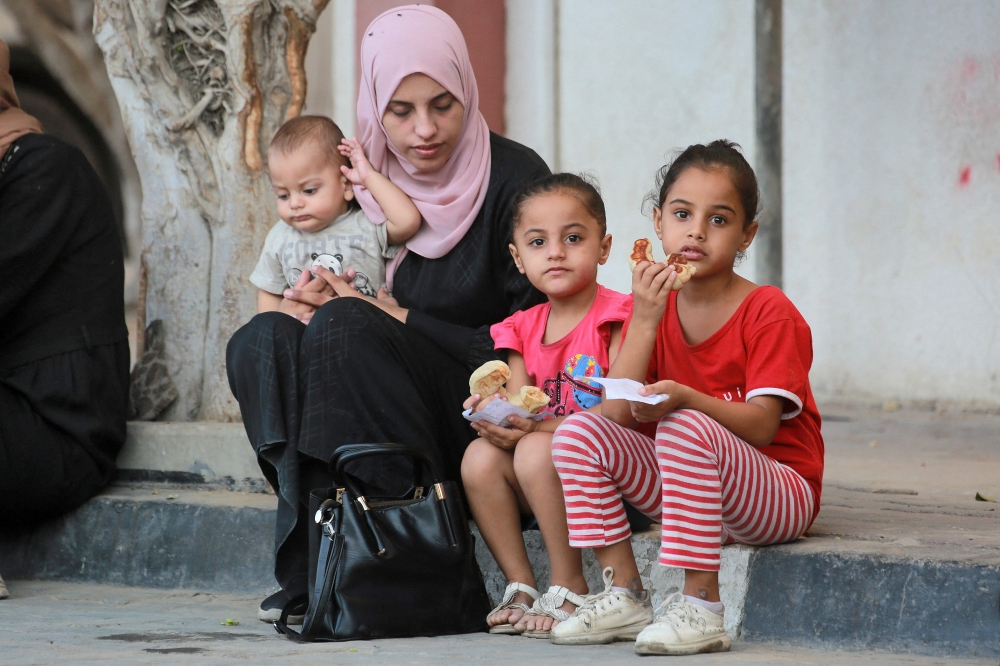 A woman waits with children for polio vaccinations in Khan Yunis in the southern Gaza Strip on September 5, 2024 amid the ongoing war in the Palestinian territory between Israel and Hamas.  (Photo by Bashar TALEB / AFP)
