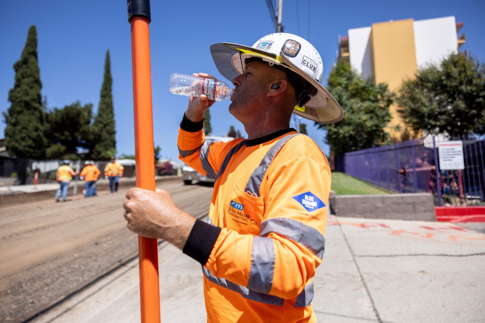 A road worker drinks water on a construction site as southern California is facing a heatwave, in Los Angeles