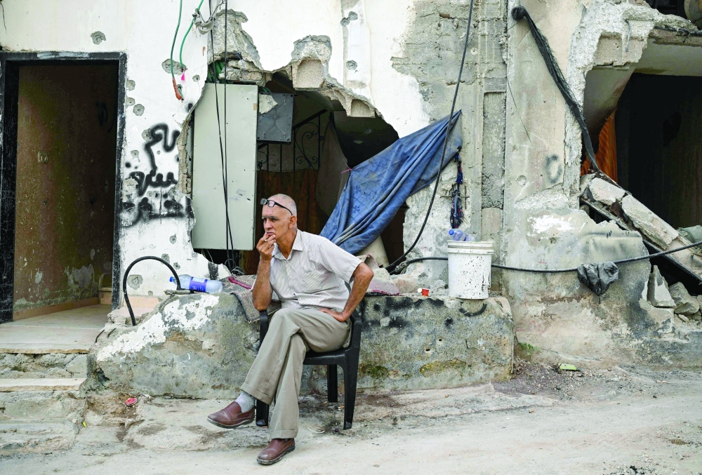 A man sits in front of a damaged building following an Israeli military raid in the Jenin refugee camp in the occupied West Bank. - AFP