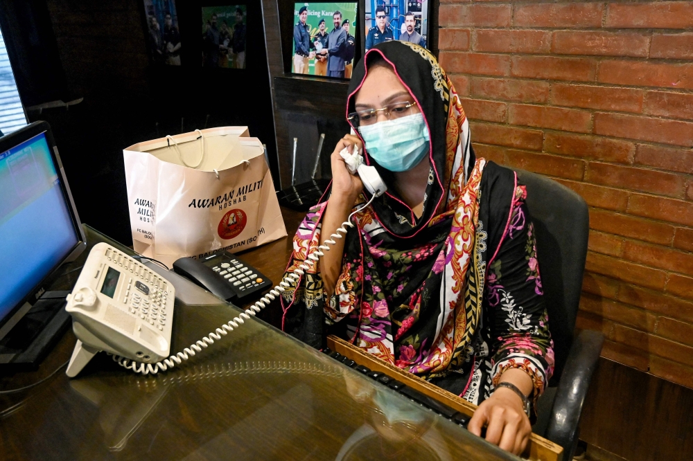 Receptionist Hina Saleem talks on the telephone at a leather factory in Karachi. 