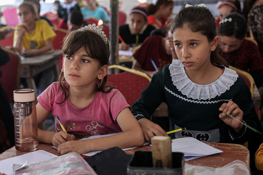 Children attend a class in a tent being used as a make-shift educational centre for primary education students in Jabalia in the northern Gaza Strip on Sunday. - AFP