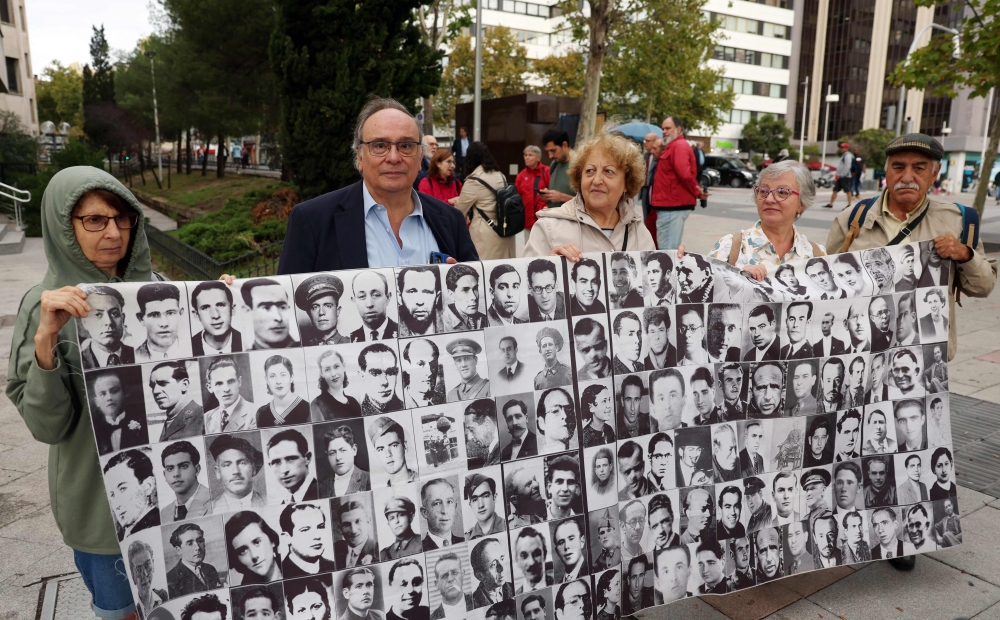 Franco's victim Julio Pacheco (2L), and his wife Rosa Maria Garcia Alcon (2R), hold a banner depicting photographs of other victims outside the courthouse in Madrid. — AFP file photo