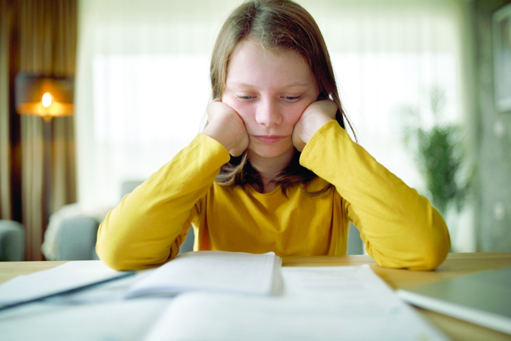 Worried young schoolgirl studying at home