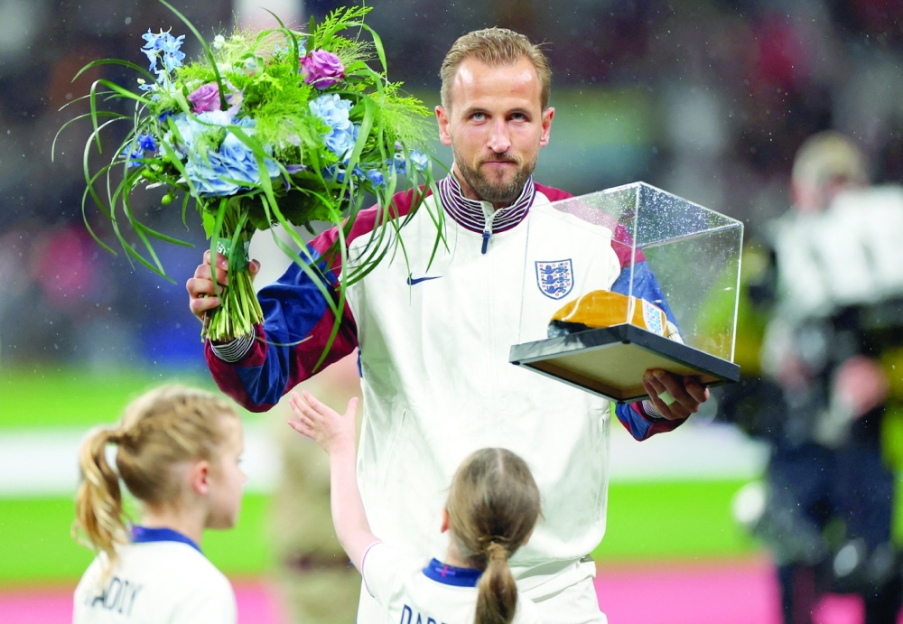 England's Harry Kane holds up a golden cap awarded for his 100th England cap with his daughters Ivy Jane Kne and Vivienne Jane before the match.