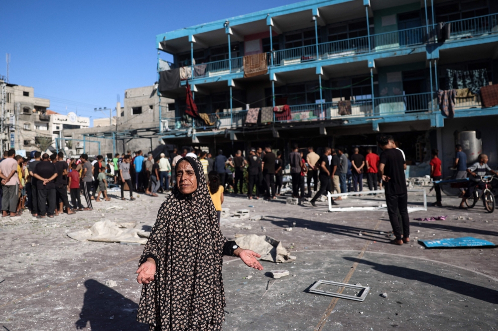 A Palestinian woman gestures at the courtyard of a school after an Israeli air strike hit the site, in Nuseirat in the central Gaza Strip. - AFP

