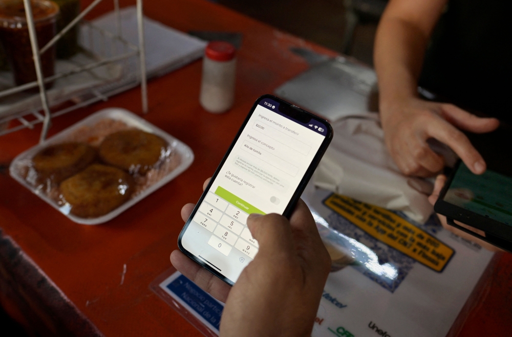 A man shows the operation of an app to buy tortillas in Mexico City