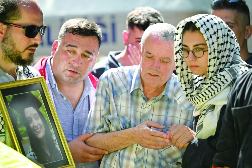 Mehmet Suat Eygi (C), father of late US-Turkish activist Aysenur Ezgi Eygi shot dead by Israeli forces mourns in front of a portrait of his daughter during her funeral ceremony at the cemetary in Didim, Aydin Province. - AFP