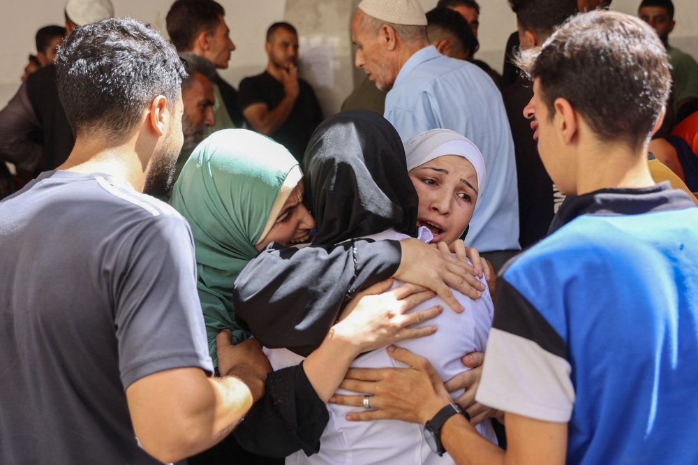 Family and friends comfort Palestinian physician Najwa Alborno (C) as bodies of five members of the Alborno family were brought to Al-Ahli Arab hospital, also known as the Baptist hospital in Gaza City on September 15, 2024, after they were killed in reported Israeli bombardment of Zeitoun neighbourhood where they had gone earlier to check on their home, amid the ongoing war between Israel and the Palestinian Hamas militant group. (Photo by Omar AL-QATTAA / AFP)

