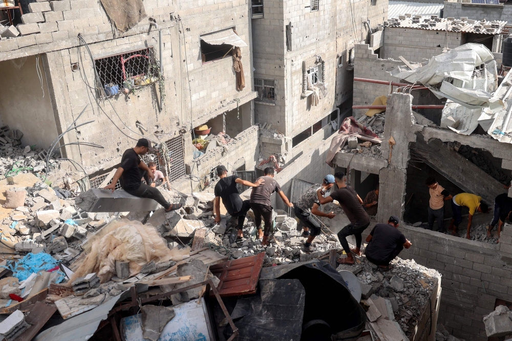 Palestinians check the rubble of a house following Israeli bombardment in Nuseirat in the central Gaza Strip. — AFP 