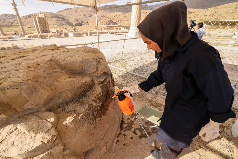 This picture taken on May 13, 2024 shows an Iranian expert inspecting a stone at the ruins of ancient Persepolis