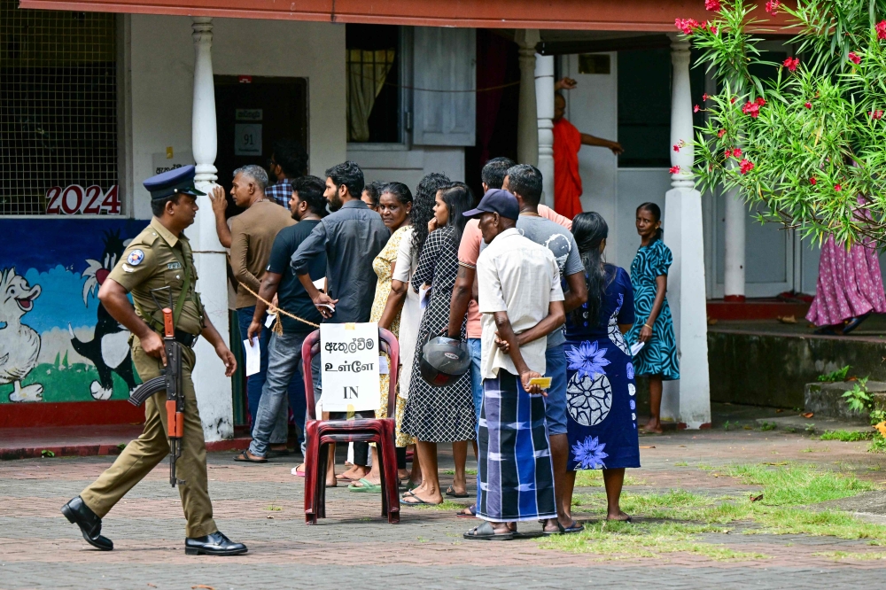 People wait in a queue to cast their ballots during voting in Sri Lanka's presidential election