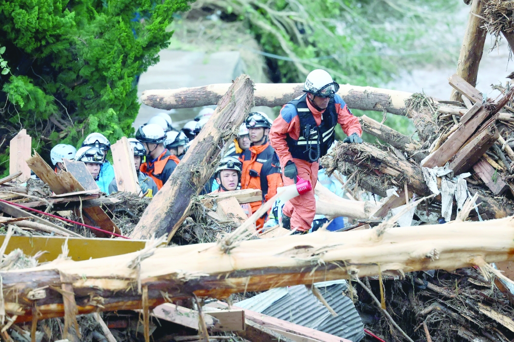 Firefighters search for missing people, through debris washed up after heavy rains caused flooding, in the city of Wajima. — AFP 