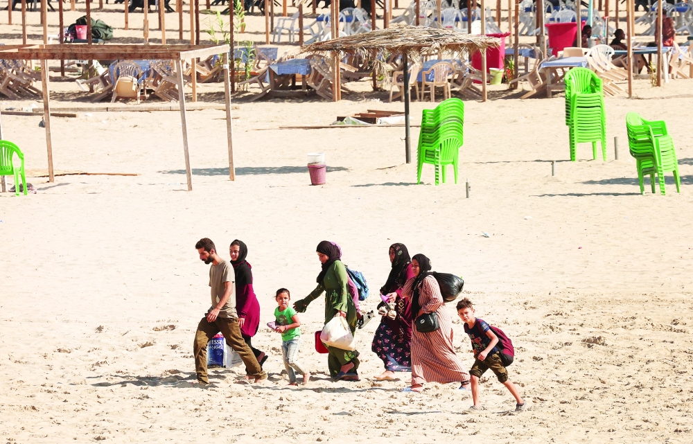 People carry belongings at a beach as they flee, in Tyre, southern Lebanon. — Reuters 