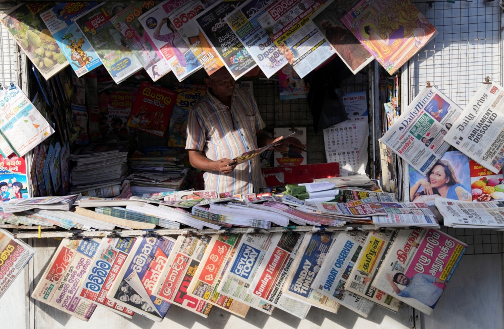 A person reads a newspaper at a stall in Colombo 