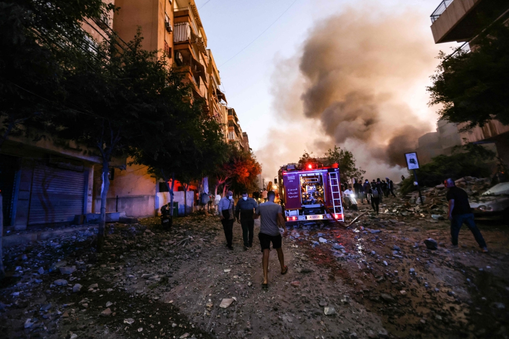 People and a fire truck rush to the scene of an Israeli air strike in the Haret Hreik neighbourhood of Beirut's  
