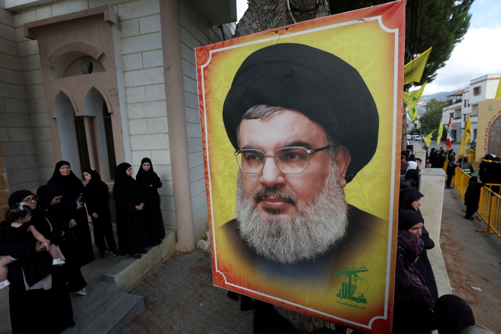 People stand near a picture of Hezbollah leader Sayyed Hassan Nasrallah