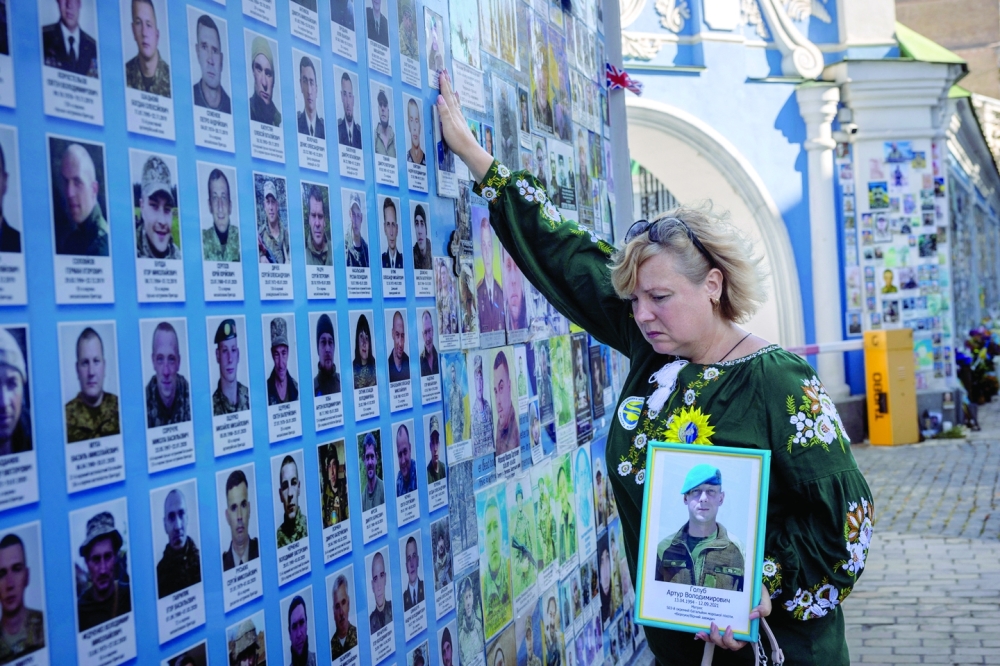 (Bitter Fight) A woman commemorates a fallen serviceman at a memorial wall, in Kyiv, Ukraine. — Reuters