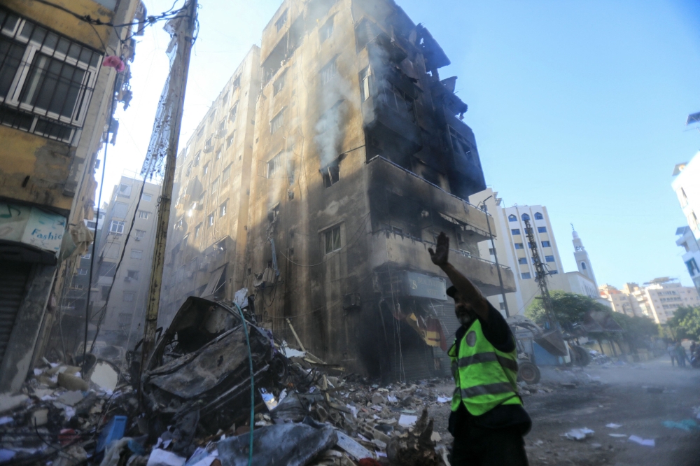 A municipal worker gestures as he stands amid the rubble next to a damaged building in the aftermath of an overnight Israeli strike in Beirut's southern suburbs. — AFP 