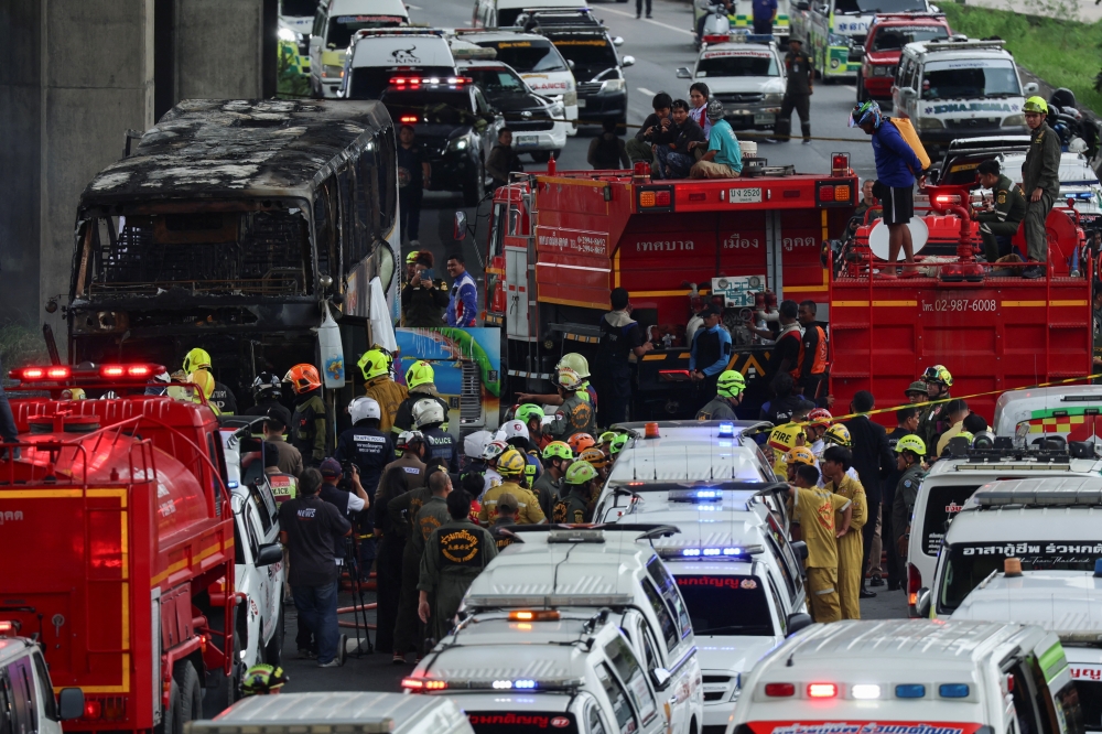 Rescue workers extinguish a burning bus carrying teachers and students from Wat Khao Phraya school, on the outskirts of Bangkok. — Reuters 