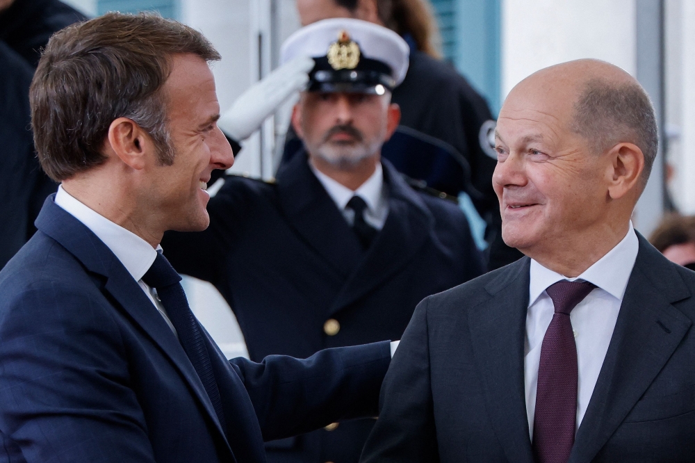 German Chancellor Olaf Scholz (R) and French President Emmanuel Macron shake hands as he arrives at the Chancellery in Berlin. — AFP 