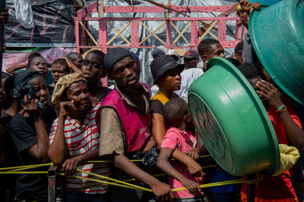 People wait for a food distribution in a displaced persons camp at the Lyc Marie Jeanne in Port-au-Prince. — AFP 