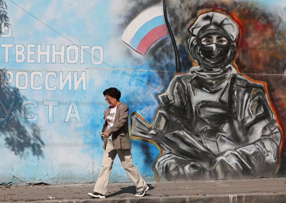 A woman walks past a mural depicting a soldier with the Russian flag in Simferopol, Crimea. — Reuters 
