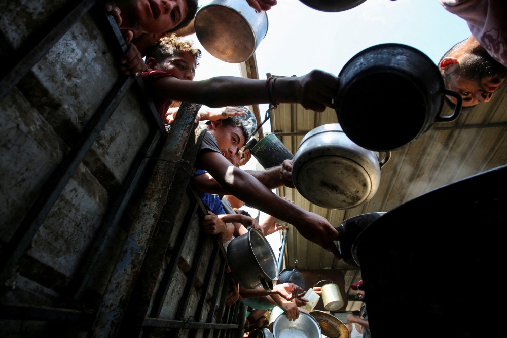 Palestinians gather to receive food cooked by a charity kitchen, in Khan Younis, southern Gaza Strip. — Reuters 