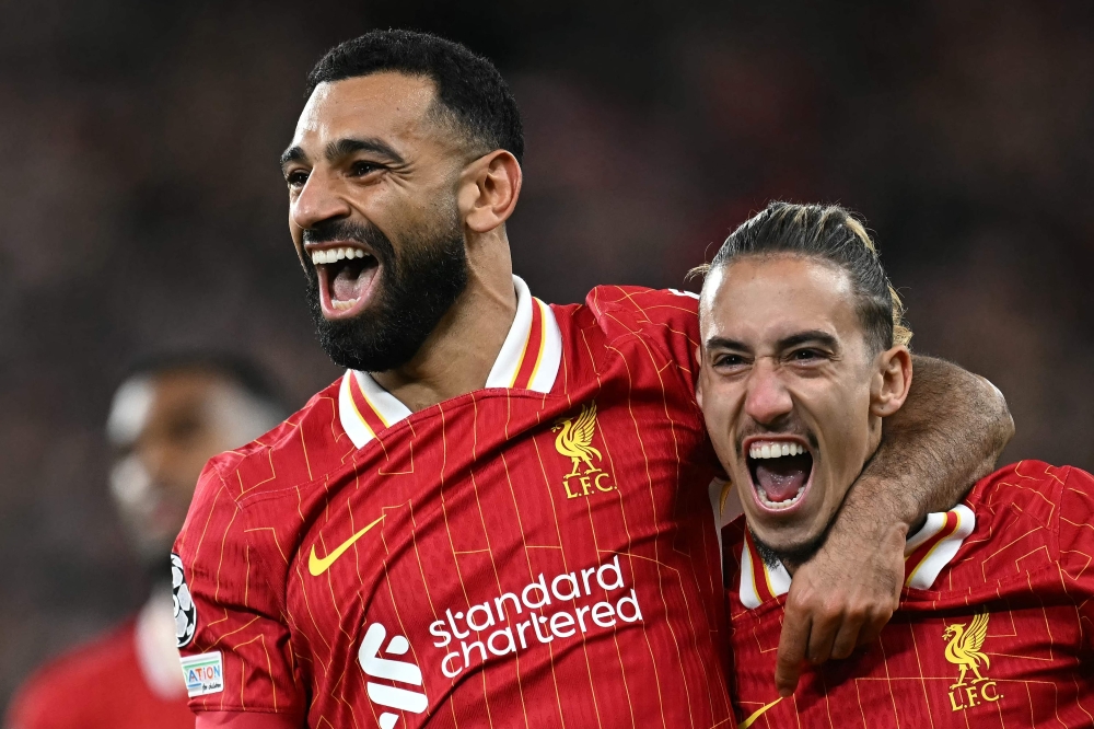 Liverpool's Egyptian striker #11 Mohamed Salah celebrates scoring the team's second goal with Liverpool's Greek defender #21 Kostas Tsimikas during the UEFA Champions League league stage football match between Liverpool and Bologna at Anfield in Liverpool, north west England on October 2, 2024.  (Photo by Paul ELLIS / AFP)

