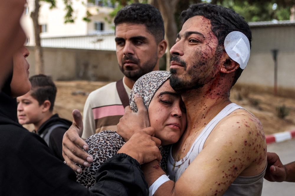 An injured man comforts a woman during a funeral for victims killed in Israeli bombardment in Khan Yunis in the southern Gaza Strip amid the ongoing war in the Palestinian territory between Israel and Hamas. - AFP


