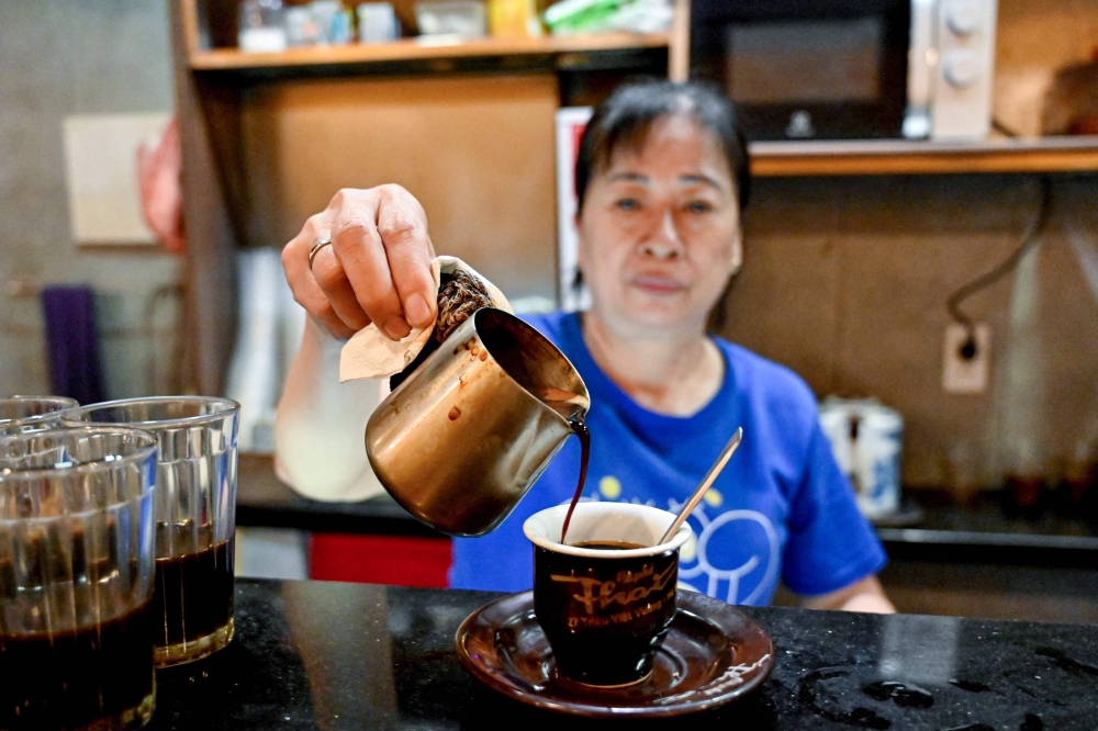 This photo taken on August 21, 2024 shows an employee making coffee for a customer at a cafe in Hanoi. Traditionally taken black, sometimes with condensed milk, salt or even egg, coffee has long been an integral part of Vietnamese culture. But running a cafe is not a career that many of Vietnam's growing group of ambitious middle-class parents would choose for their children. - To go with 'VIETNAM-COFFEE-CAFE,FOCUS' by Alice Philipson and Lam Nguyen
 (Photo by Nhac NGUYEN / AFP) / To go with 'VIETNAM-COFFEE-CAFE,FOCUS' by Alice Philipson and Lam Nguyen

