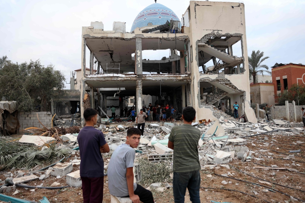  Palestinian stare at a mosque-turned-shelter in Deir al-Balah in the central Gaza Strip, heavily damaged in an Israeli strike. — AFP 