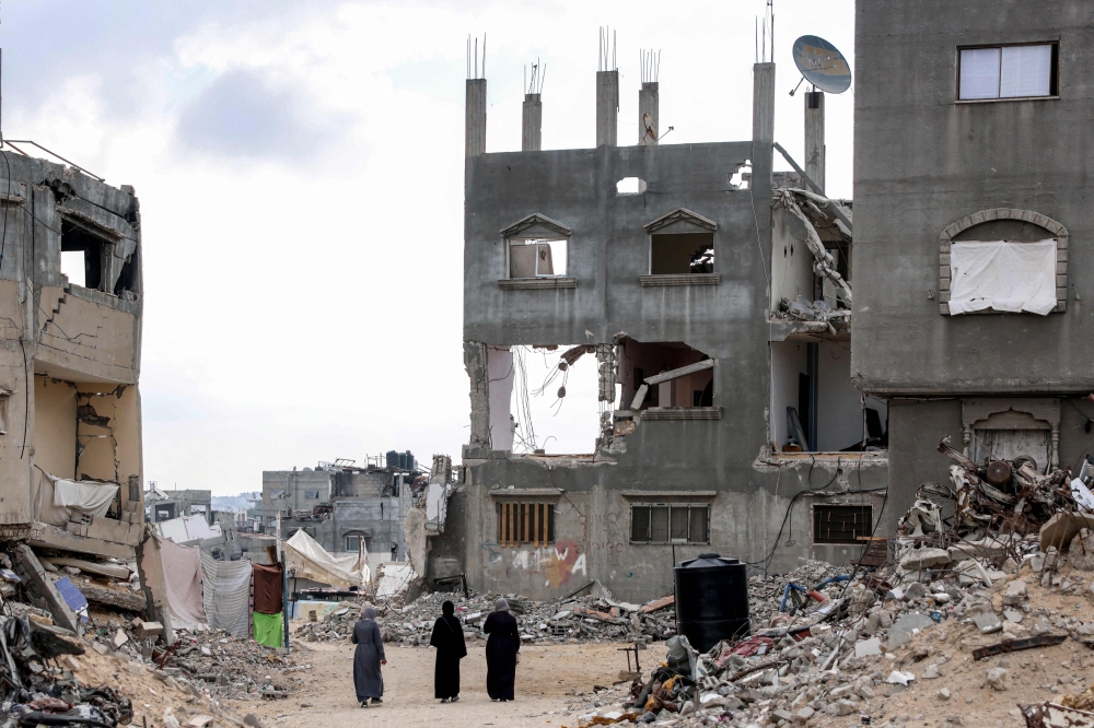 Three women walk past destroyed buildings in Khan Yunis in the southern Gaza Strip on October 7, 2024 on the first anniversary of the ongoing war in the Palestinian territory between Israel and Hamas.