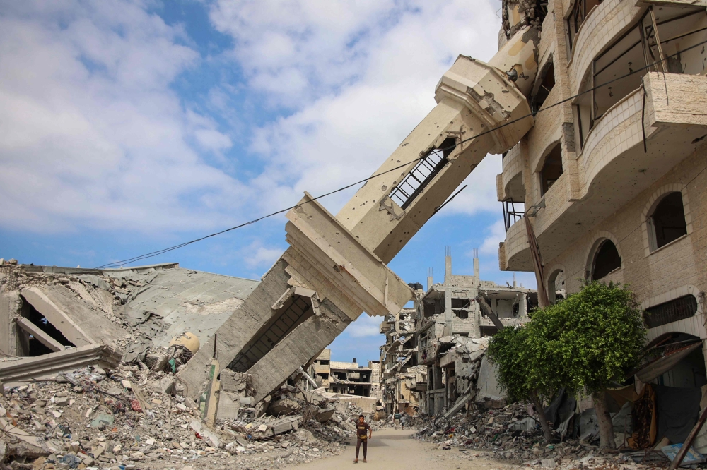 Palestinians walk beneath the tilted minaret of a destroyed mosque in the Shujaiya neighbourhood of Gaza City on Monday, on the first anniversary of the ongoing war in the Gaza Strip between Israel and Hamas. — AFP

