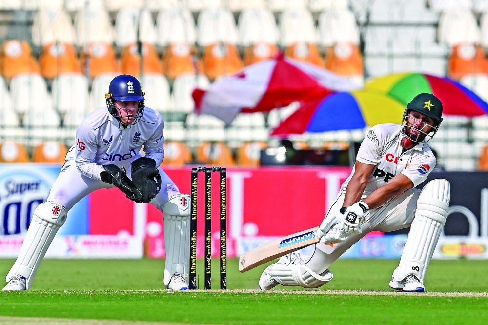 Pakistan's Agha Salman (R) plays a shot as England's wicketkeeper Jamie Smith watches during the second day of the first Test cricket match between Pakistan and England at the Multan Cricket Stadium in Multan on October 8, 2024.  (Photo by Aamir QURESHI / AFP)

