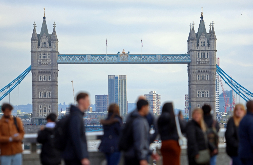 People walk looking at a view of Tower Bridge in the City of London financial district in London. — Reuters file photo
