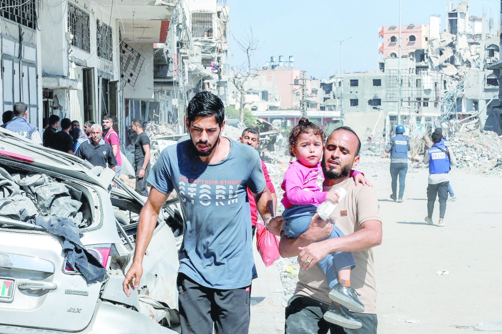 A man carries a child while evacuating in the Jabalia camp for Palestinian refugees in the northern Gaza Strip on Wednesday. — AFP