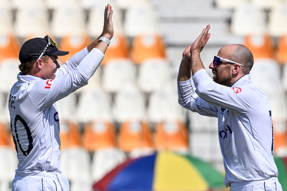 England's captain Ollie Pope celebrates with teammate Jack Leach (R) after winning the first Test cricket match between Pakistan and England