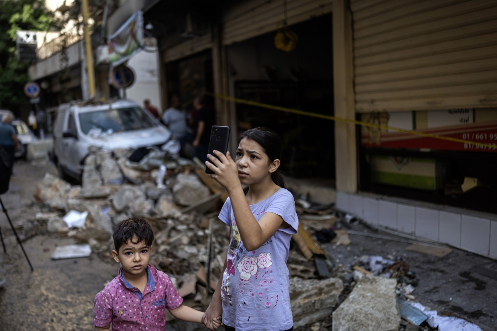 A young girl uses a smartphone to document the devastation in a central Beirut neighborhood on Friday, Oct. 11, 2024. Lebanese officials said Israeli airstrikes killed at least 22 people and wounded more than 100. The Israeli military did not confirm the strike. (David Guttenfelder/The New York Times)
