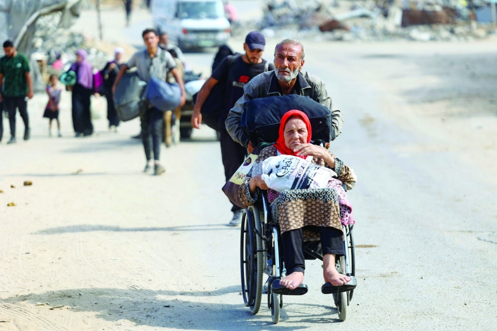 A man pushes the wheelchair of a woman as Palestinians carrying their belongings flee areas north of Gaza City in the northern Gaza Strip on Saturday. - AFP