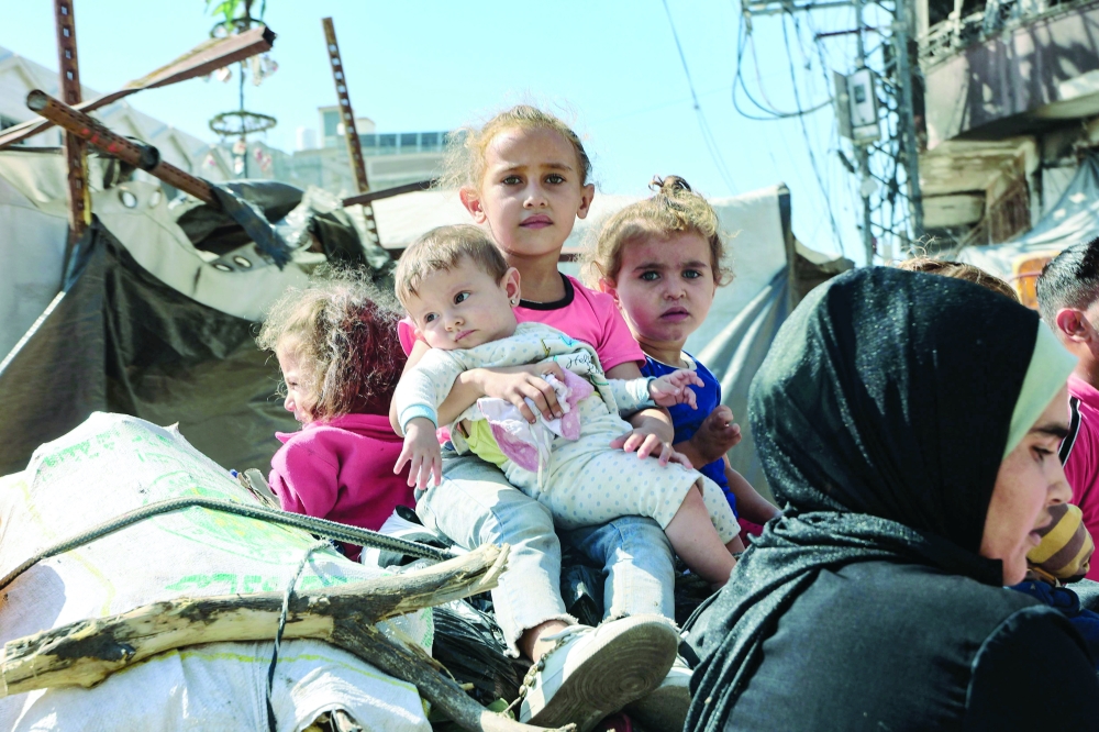 Palestinian children sit atop their family's belongings as they flee areas north of Gaza City in the northern Gaza Strip on Saturday. - AFP

