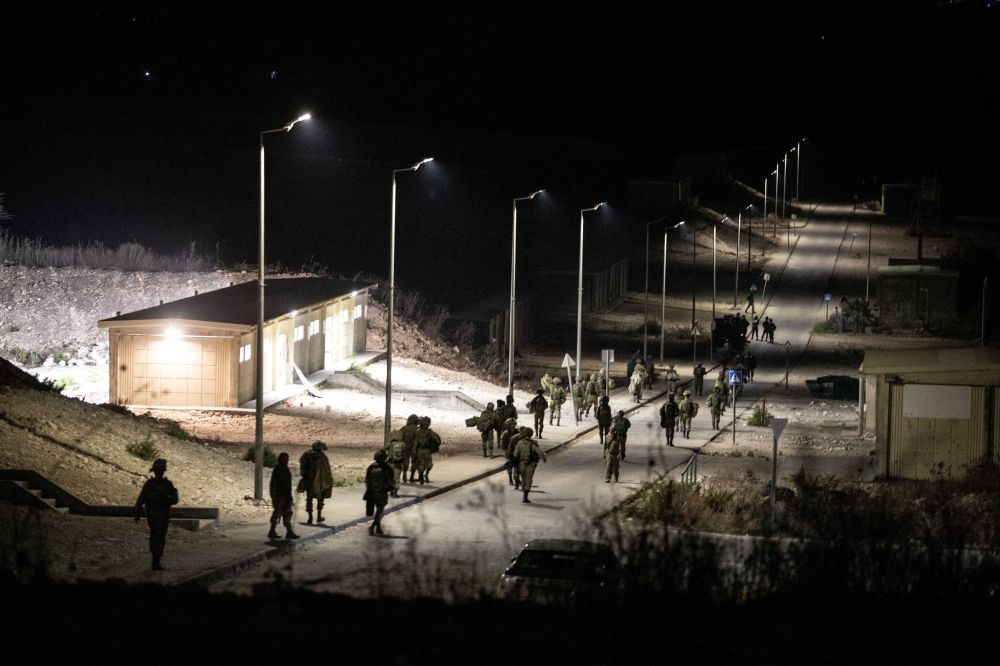 Israeli soldiers walk near the scene where a drone from Lebanon attacked Israel