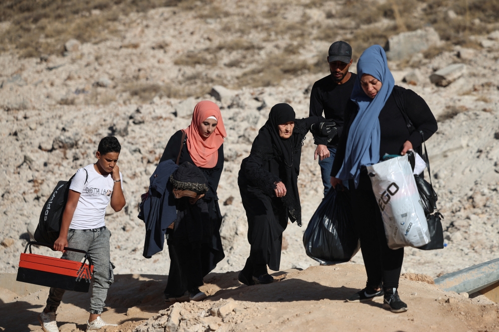 People carry their belongings while crossing from Lebanon into Syria on foot at the Masnaa border crossing. — Reuters