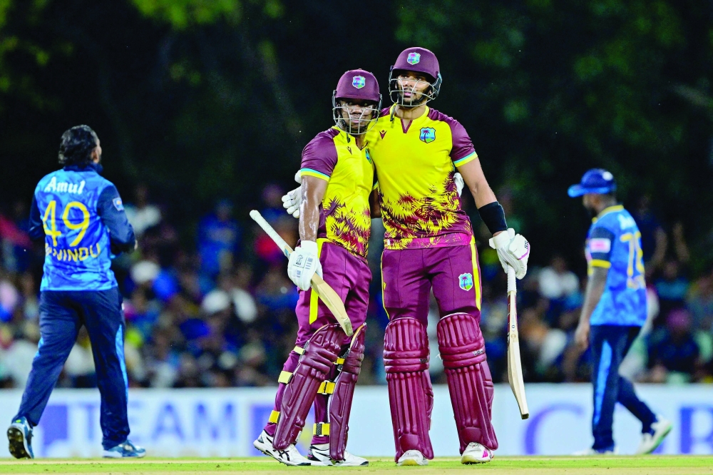 West Indies' Evin Lewis (R) celebrates with Brandon King (L) after scoring a half-century (50 runs) during the first Twenty20 international cricket match between Sri Lanka and West Indies at the Rangiri Dambulla International Cricket Stadium in Dambulla on October 13, 2024.  